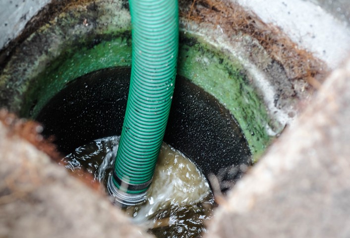 Manguera de un camión cuba dentro de un pozo negro con agua turbia en Agüimes